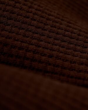 A close-up view of the brown 100% cotton fabric with a waffle weave pattern, reminiscent of the exquisite texture found in Dandy Del Mar's The Cannes Waffle Knit Robe - Carajillo.