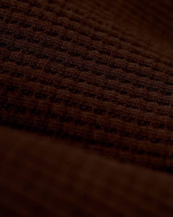 A close-up view of the brown 100% cotton fabric with a waffle weave pattern, reminiscent of the exquisite texture found in Dandy Del Mar's The Cannes Waffle Knit Robe - Carajillo.