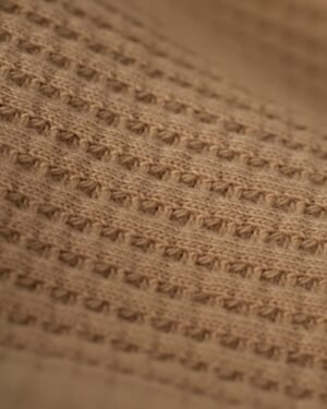 Close-up of the beige waffle knit fabric with a textured pattern of horizontal and vertical stitches, showcasing the embroidered Dandy Del Mar logo on The Cannes Long Sleeve Shirt - Truffle.