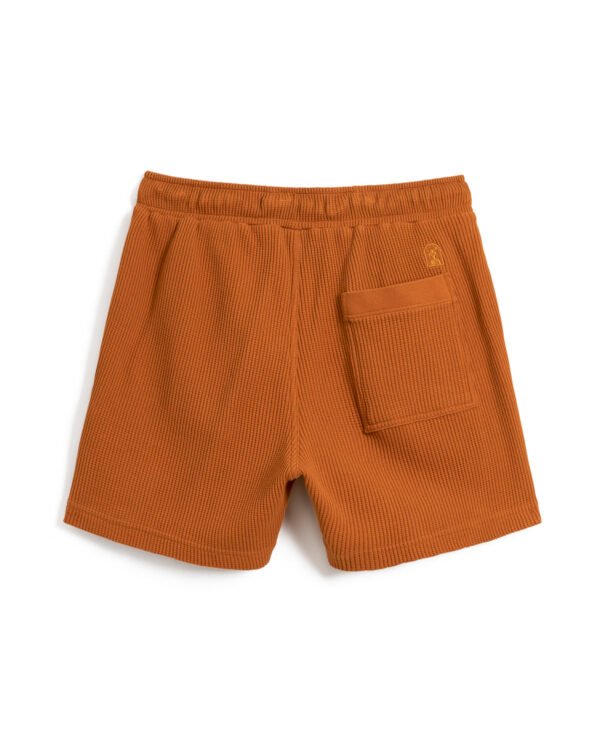 A pair of orange ribbed shorts with an elastic waistband, crafted from 100% cotton waffle knit fabric, featuring a convenient back pocket is now replaced by The Cannes Waffle Knit Shorts - Burnt Sienna from Dandy Del Mar.