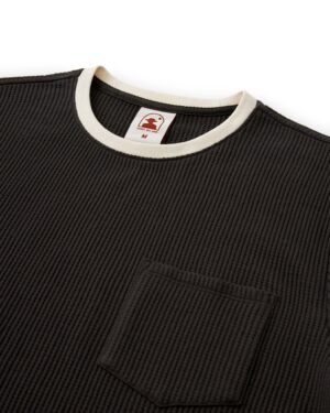 The Cannes Waffle Knit Tee - Albatross by Dandy Del Mar is a stylish black textured shirt with a waffle knit, featuring a round white-edged neckline, chest pocket, and an inner collar label with tree logo and size 