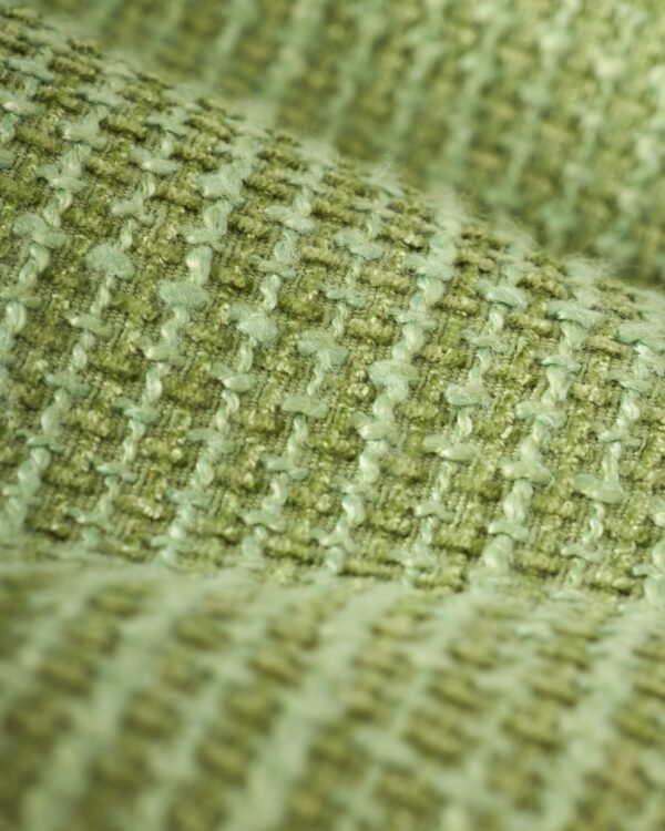 Close-up of The Trinidad Tweed Strapless Dress - Oliva by Dandy Del Mar, featuring textured green fabric with a woven pattern reminiscent of classic tweed, showcasing raised and indented areas.