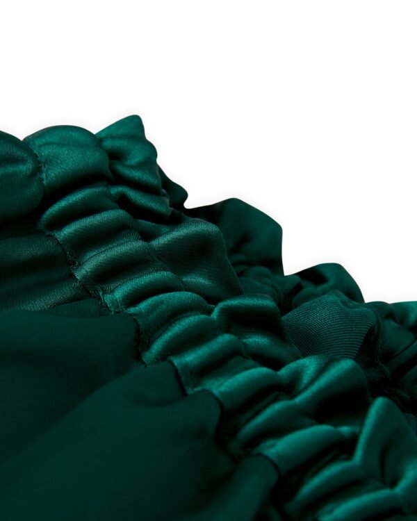 Close-up of the gathered green satin fabric with ruffled edges of The Monaco Flounce Top - Albero by Dandy Del Mar.