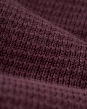 A detailed view of The Sebastian Long Sleeve Polo in Amethyst by Dandy Del Mar highlights the textured, sweater-knit cotton fabric and its intricate pattern.