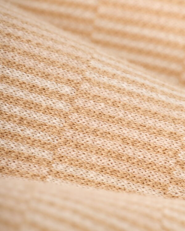 Close-up of The Sebastian Knit Polo - Shell by Dandy Del Mar, showcasing a beige Italian knit fabric with textured pattern and alternating light and dark stripes.