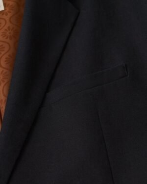 A close up of the Dandy Del Mar Brisa Linen Blazer - Onyx with a brown pocket.