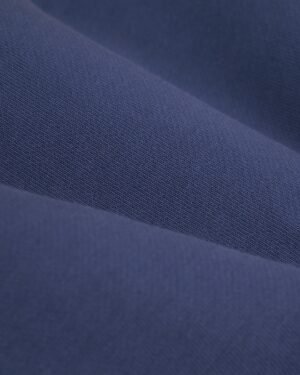 A close-up image of blue fabric with a smooth texture and a tightly woven pattern, reminiscent of the classic French Terry used in the stylish 