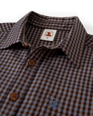 A close-up of the Tresco Shirt - Tierra Houndstooth by Dandy Del Mar, a brown and blue checkered woven collared button-up featuring a brand label marked 