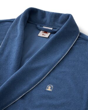 The Tropez Robe - Annapolis by Dandy Del Mar is an ultra-soft blue bathrobe with white piping, crafted from Terry Cloth. It includes a small embroidered logo, a size tag for M/L in the collar, and offers an above-the-knee fit for style and comfort.