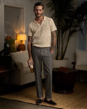 A man standing in a living room holding The Antibes Crochet Shirt - Vintage Ivory by Dandy Del Mar.
