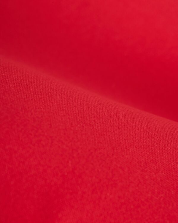 Close-up view of a textured red fabric with a soft appearance and slight shading variations, reminiscent of the luxurious recycled nylon used in Dandy Del Mar's The Avila Top - Pico's supportive underwire design.