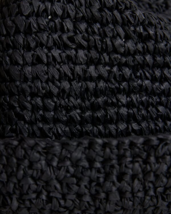 Close-up view of a textured black fabric with a detailed raffia-effect crochet pattern on The Amabile Raffia Hat in Onyx by Dandy Del Mar.