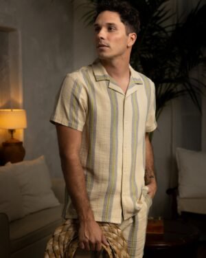 A man in striped pajamas standing in a living room wearing a Dandy Del Mar Corralejo Shirt in Ginger.