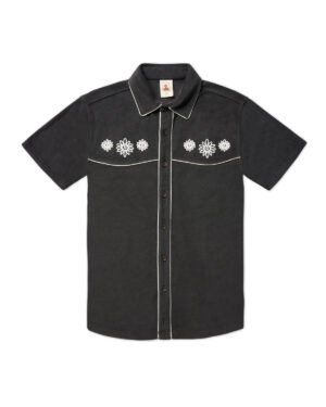 The Gaucho Shirt - Onyx by Dandy Del Mar is a black short-sleeve shirt featuring white floral embroidery on the chest, white piping along the edges, and a seven-button closure.